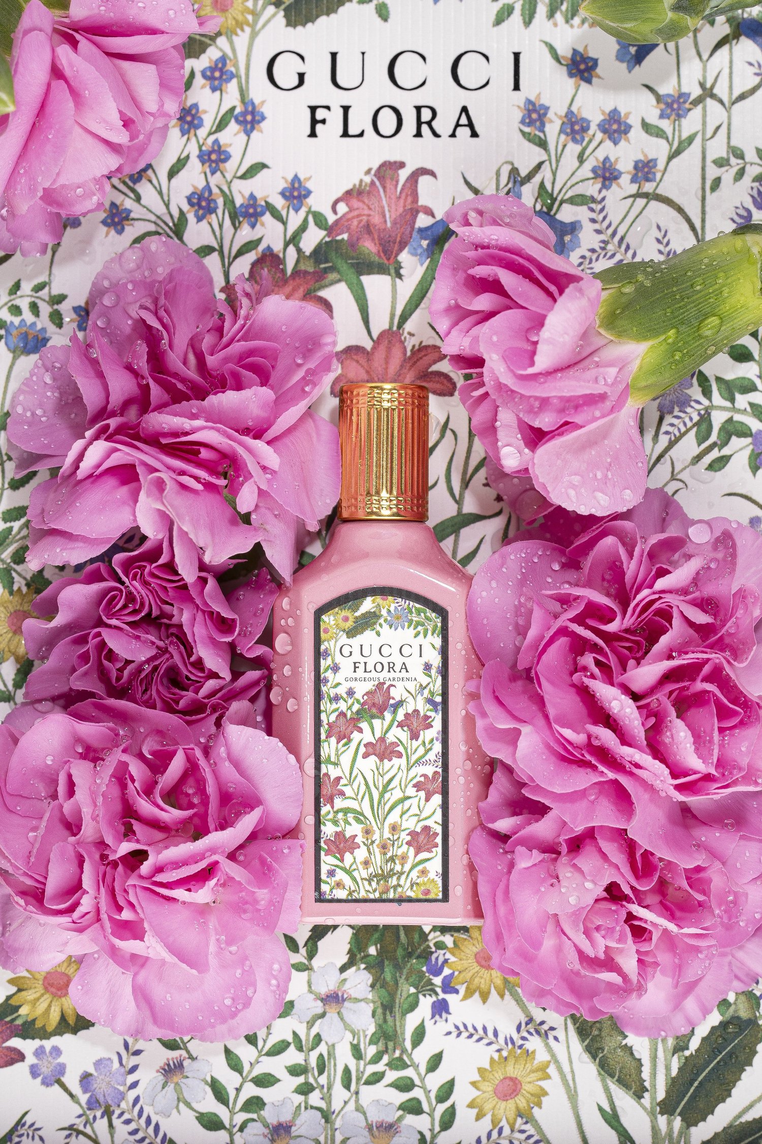 A Gucci Flora fragrance bottle photographed with pink roses and its floral packaging.